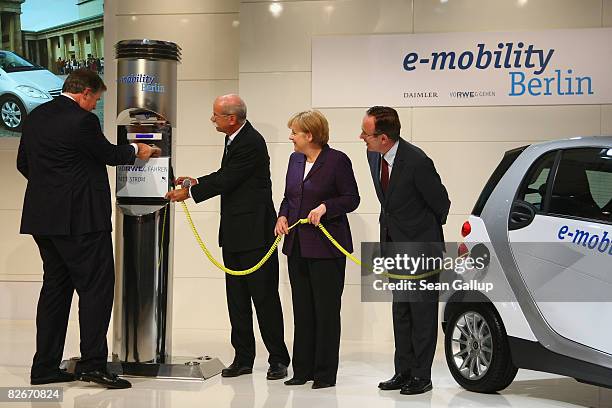 Juergen Grossmann , CEO of German power supplier RWE, attempts to start the charging of an electric Smart car as German Chancellor Angela Merkel,...