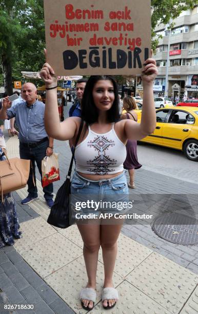 Woman holds up a sign that reads, 'My dress is not an invitation to you' during a protest in Kugulu Park in Ankara on August 5 to demand the right...