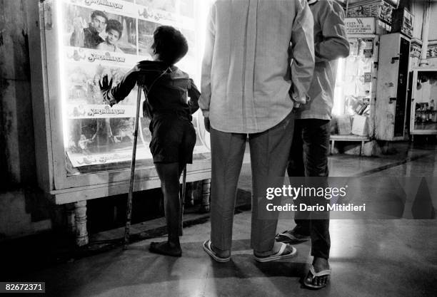 Street child Gangaram, a boy with polio from Maharashtra, looks at a poster of the latest Hindi film inside Victoria Terminus station in Bombay,...