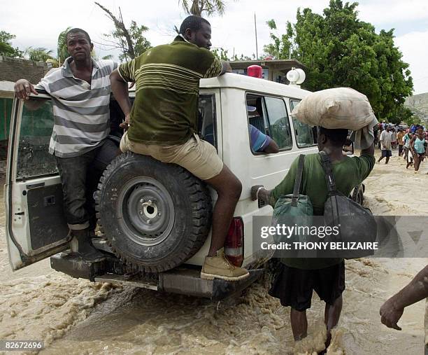 People follow a Red Cross vehicle through a flooded street on September 5, 2008 in Gonaives, 171 Km from Port-au-Prince after the passing of Tropical...