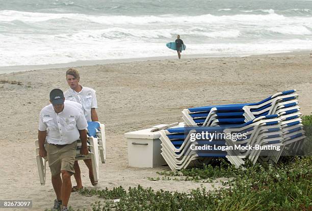Employees at the Blockade Runner Hotel remove outdoor furniture in preparation for winds and rains anticipated with the arrival of Tropical Storm...