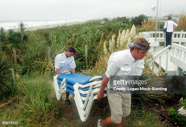 Employees at the Blockade Runner Hotel remove outdoor furniture in preparation for winds and rains anticipated with the arrival of Tropical Storm...