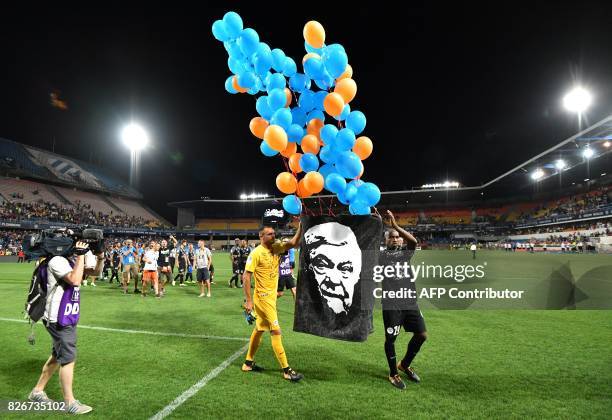 Montpellier's Senegalese forward Souleymane Camara and Montpellier's French goalkeeper Laurent Pionnier hold a portrait of Montpellier's late...