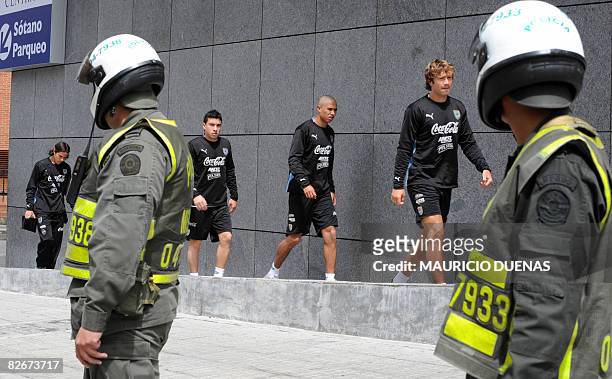 Uruguayan football players Jorge Rodriguez, Diego Arismendi and Sebastian Fernandez walk next to Colombian policemen prior to a training session on...