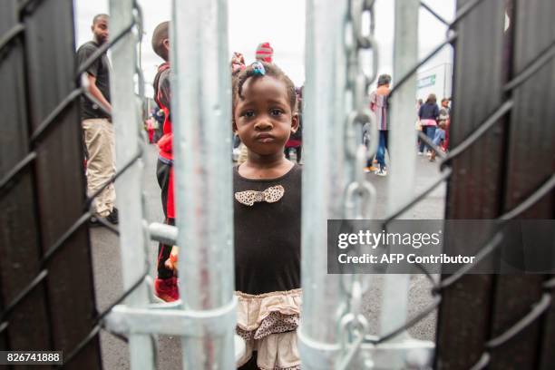 Girl who crossed the Canada/US border illegally with her family, claiming refugee status in Canada, looks through a fence at a temporary detention...