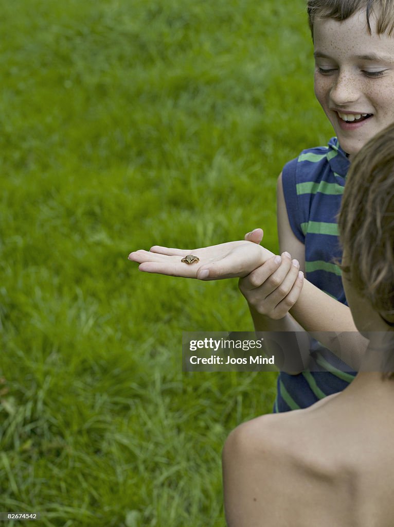 Two boys holding frog, laughing