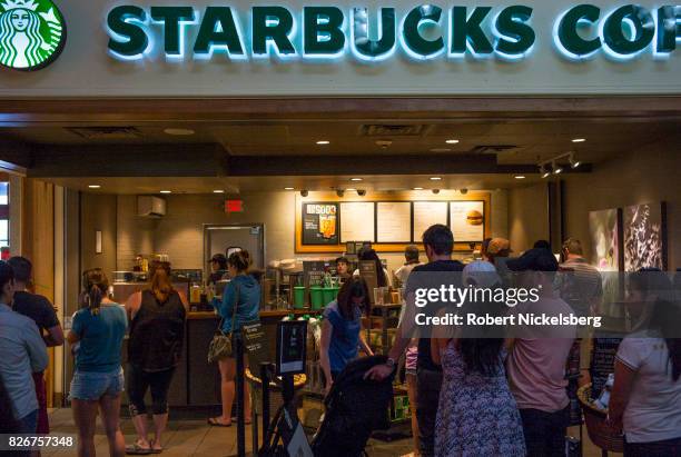 Customers stand in line at a Starbucks Coffee shop July 30, 2017 along the New York State Thruway in Plattekill, New York. Starbucks was founded in...