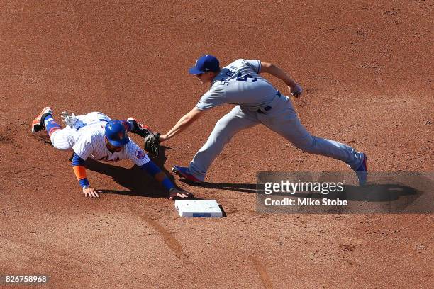Corey Seager of the Los Angeles Dodgers applies the tag late as Rene Rivera of the New York Mets slides into second safley in the second inning at...