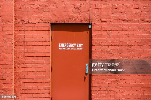 gleaming red wall with red emergency exit door - workplace evacuation stock pictures, royalty-free photos & images