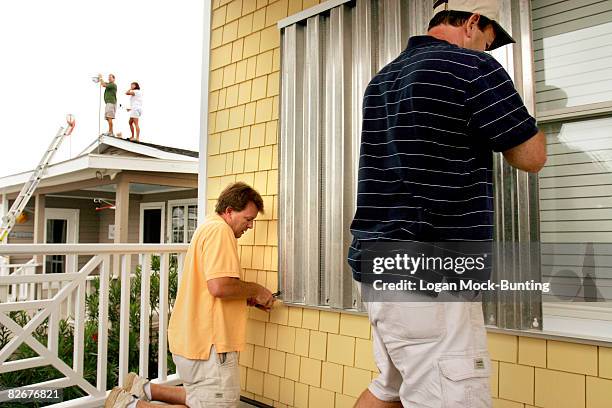 David Manning and Mark Manning installs metal storm shutters in preparation for winds and rains anticipated with the arrival of Tropical Storm Hannah...