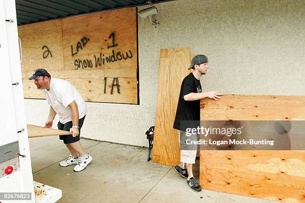 Employees at Redix Beach Store move plywood to be used for boarding up windows and doors in preparation for winds and rains anticipated with the...