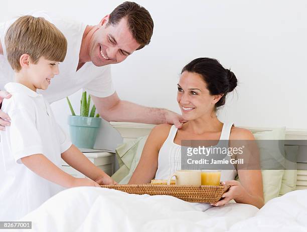 son and father bringing mother breakfast in bed - mother's day breakfast stock pictures, royalty-free photos & images