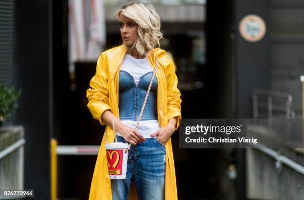 Model and fashion blogger Gitta Banko wearing a long yellow patent-leather coat by Marina Hoermanseder, a white t-shirt by James Perse under a demin...