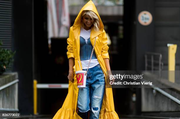 Model and fashion blogger Gitta Banko wearing a long yellow patent-leather coat by Marina Hoermanseder, a white t-shirt by James Perse under a demin...