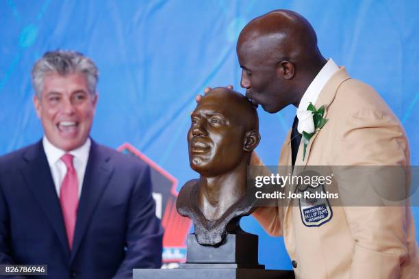 Terrell Davis kisses his bust as presenter Neil Schwartz looks on during the Pro Football Hall of Fame Enshrinement Ceremony at Tom Benson Hall of...