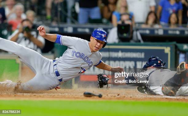 Rob Refsnyder of the Toronto Blue Jays avoids the tag of Brian McCann of the Houston Astros as he scores on a single by Ryan Goins of the Toronto...