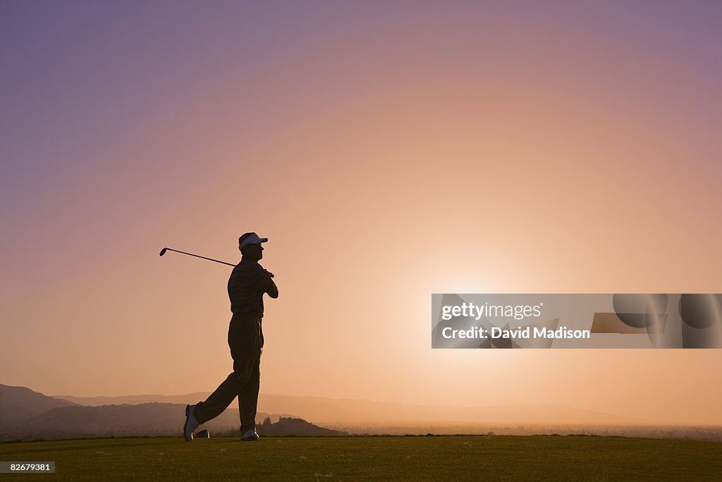 Male golfer following through after drive.