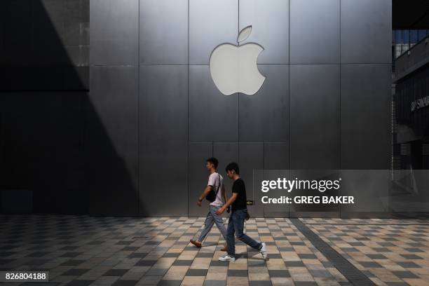 This photo taken on August 3, 2017 shows people walking past an Apple store in Beijing. - Enterprising internet users in China fear the tools they...