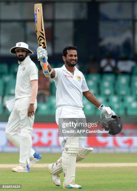 Sri Lanka's Dimuth Karunaratne raises his bat and helmet in celebration after scoring a century during the fourth day of the second Test match...