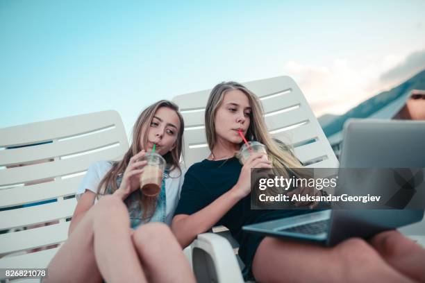 smiling females drinking coffee and watching movies at summer beach - get out film 2017 stock pictures, royalty-free photos & images