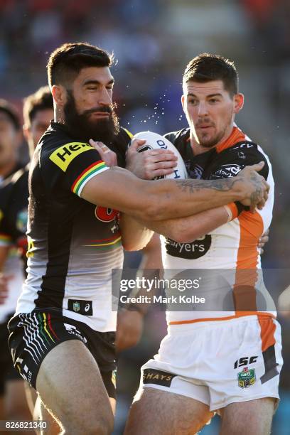 Matthew Eisenhuth of the Tigers is tackled by James Tamou of the Panthers during the round 22 NRL match between the Penrith Panthers and the Wests...