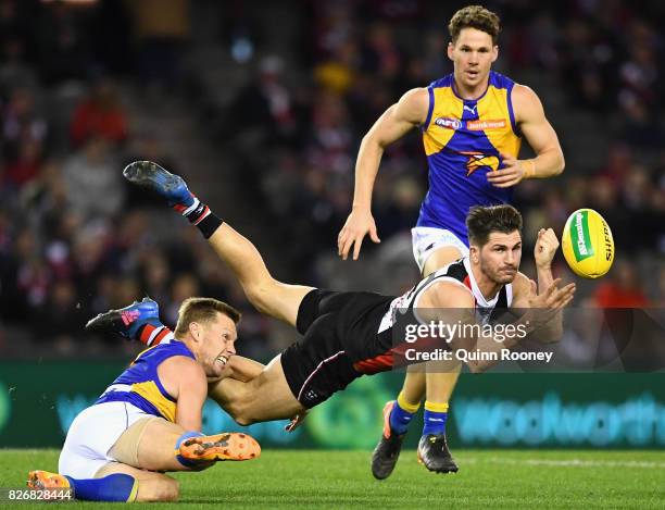 Koby Stevens of the Saints handballs whilst being tackled by Sam Mitchell of the Eagles during the round 20 AFL match between the St Kilda Saints and...