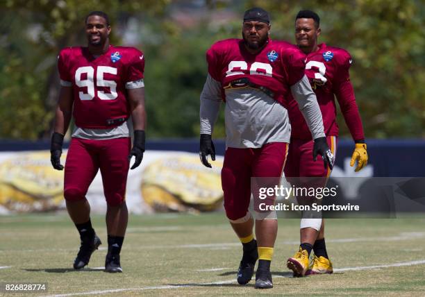 Washington Redskins defensive lineman Jonathan Allen , A.J. Francis and Brandon Banks walk onto the field prior to conditioning drills during...