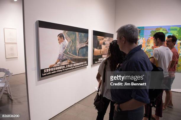 Art patrons examine large paintings by Chow Chun Fe during the Seattle Art Fair at CenturyLink Field on August 5, 2017 in Seattle, Washington.