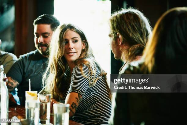 smiling woman hanging out with friend while having drinks in bar - flirting imagens e fotografias de stock