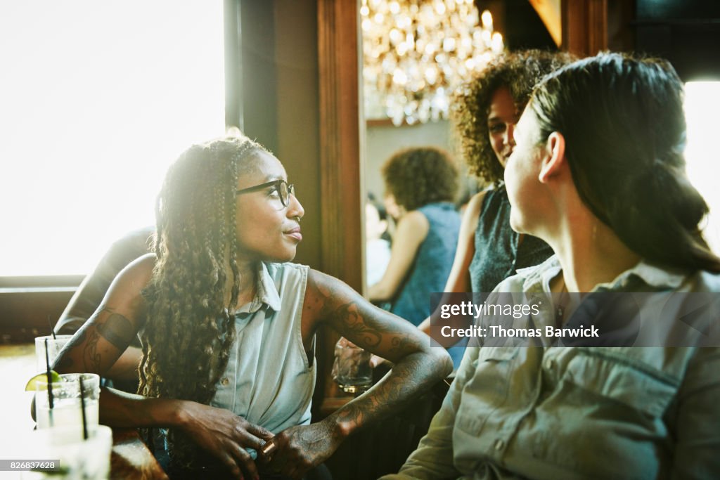 Female friends in discussion while hanging out in bar