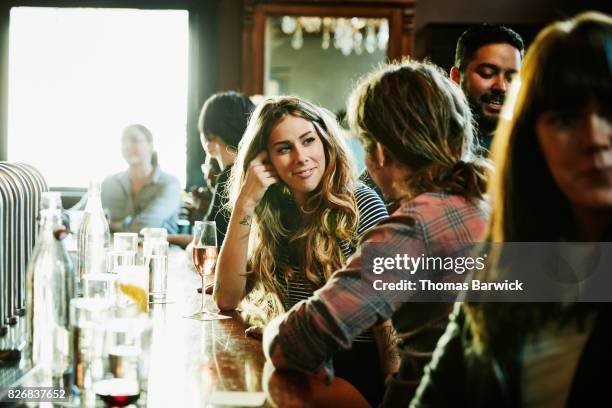 smiling woman flirting with man while sitting in bar - conquista fotografías e imágenes de stock