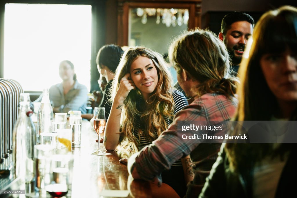 Smiling woman flirting with man while sitting in bar