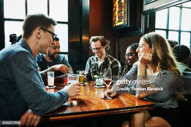 smiling friends sharing drinks at table in bar - hair color saloon stockfoto's en -beelden