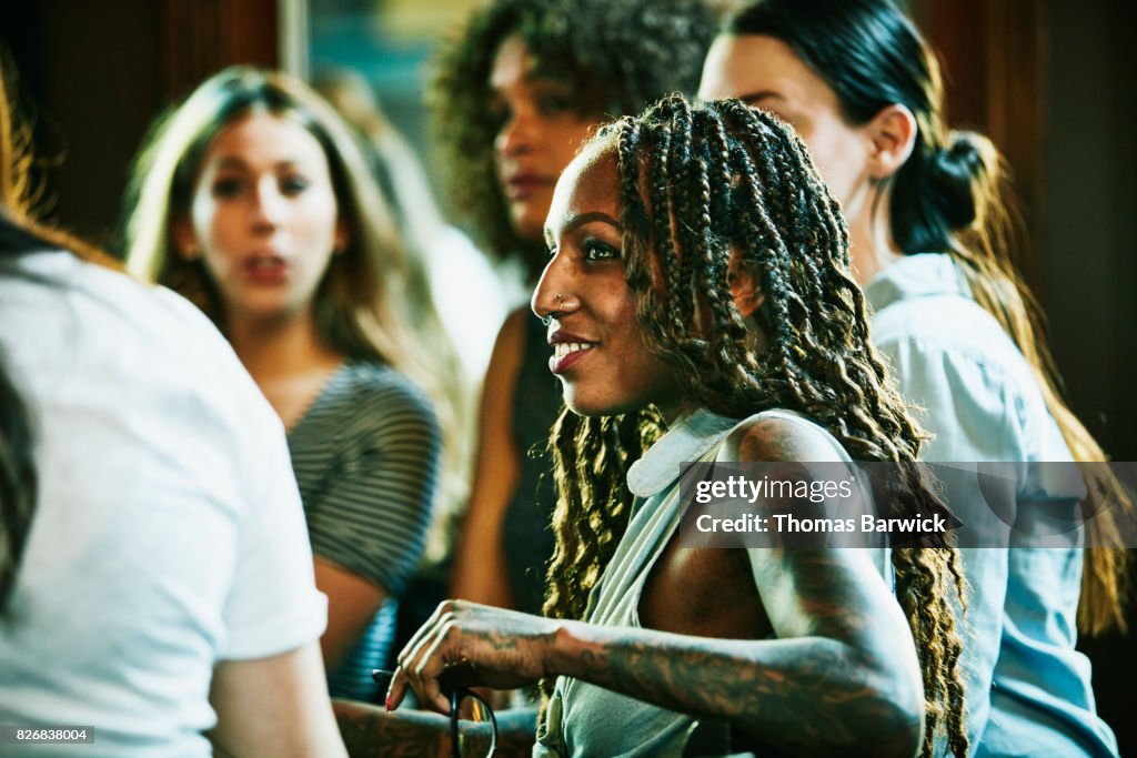 Smiling woman in discussion with friends in bar