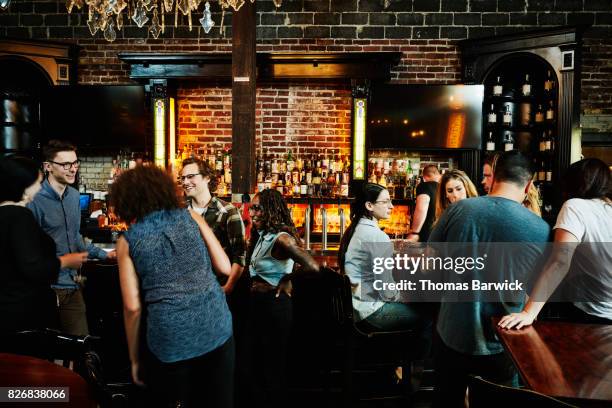 group of friends sharing drinks in busy bar - amigos bar fotografías e imágenes de stock