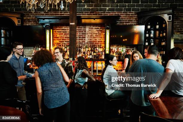 group of friends sharing drinks in busy bar - bar people foto e immagini stock