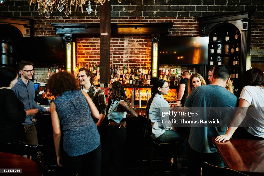 Group of friends sharing drinks in busy bar