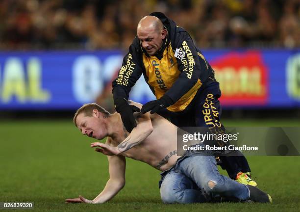 Pitch invader is tackled by security during the round 20 AFL match between the Richmond Tigers and the Hawthorn Hawks at Melbourne Cricket Ground on...