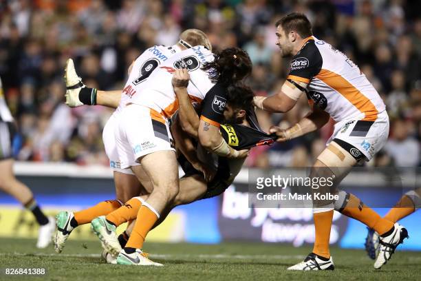 Jacob Liddle, Aaron Woods and Tim Grant of the Tigers tackle James Tamou of the Panthers during the round 22 NRL match between the Penrith Panthers...