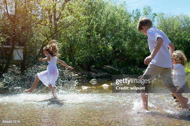 children running through and kicking water - zest ford stock pictures, royalty-free photos & images