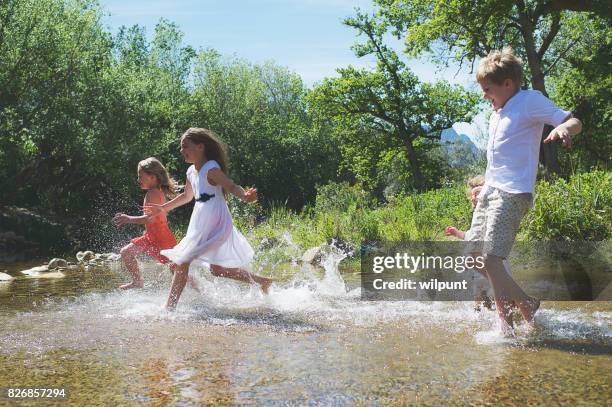 children running through water - zest ford stock pictures, royalty-free photos & images