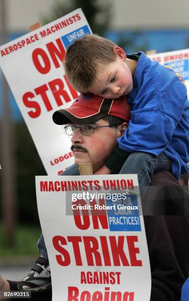 Boeing machinist Scott Green, with his son Joshua on his shoulders, walks the picket line outside Boeing's plant September 6, 2008 in Everett,...