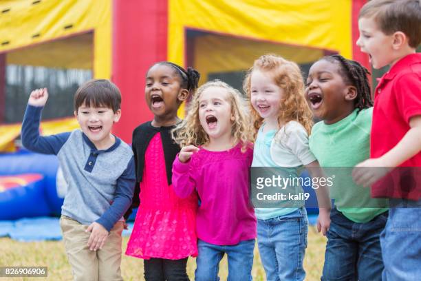 multi-ethnic children shouting, next to bounce house - school fete stock pictures, royalty-free photos & images