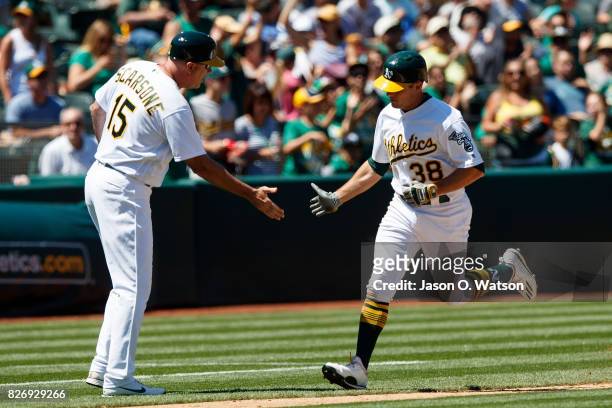 Jaycob Brugman of the Oakland Athletics is congratulated by third base coach Steve Scarsone after hitting a home run against the Minnesota Twins...