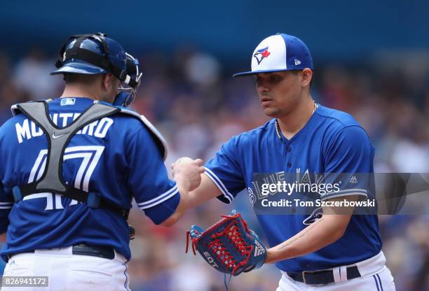 Roberto Osuna of the Toronto Blue Jays gets the ball from Miguel Montero in the ninth inning during MLB game action against the Los Angeles Angels of...