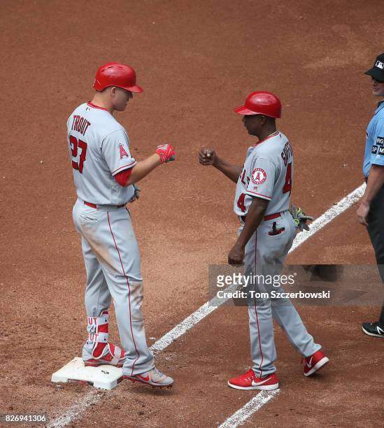 Mike Trout of the Los Angeles Angels of Anaheim is congratulated by first base coach Alfredo Griffin after hitting an RBI single in the sixth inning...