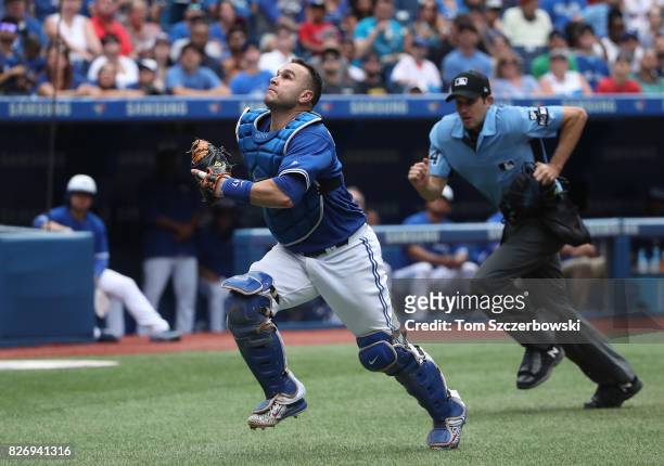Miguel Montero of the Toronto Blue Jays chases a foul pop up as home plate umpire John Tumpane follows in the ninth inning during MLB game action...