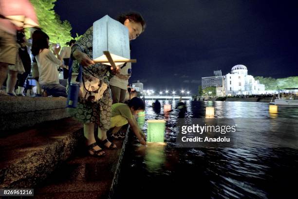 People attend the Peace Message Lantern Floating Ceremony held to console the souls of the A-Bomb victims after the Hiroshima Peace Memorial Ceremony...