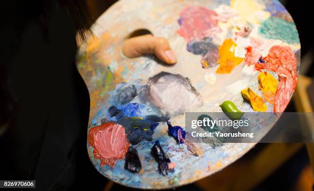 artist brush mix color oil painting on palette is holding in his hand closeup - palet stockfoto's en -beelden