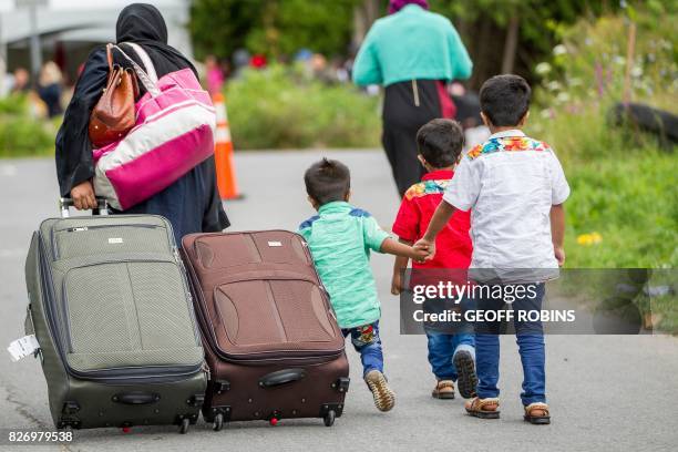 Asylum seekers walk along Roxham Road near Champlain, New York on August 6 making their way towards the Canada/US border. - In recent days the number...